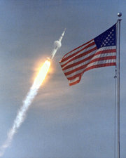 A condensation cloud is seen sticking to the Apollo 11 Saturn V launch vehicle as it works its way up through the dense, lower atmosphere.