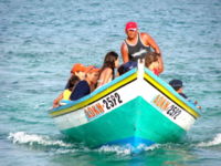 A wooden boat operating near shore.