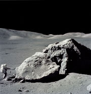 Apollo 17 astronaut Harrison Schmitt standing next to boulder at Taurus-Littrow during third EVA (extravehicular activity). NASA photo.