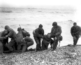 Survivors of a sunken troop transport wade ashore on Omaha Beach