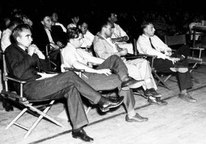 A group of physicists at a wartime Los Alamos colloquium. In the front row are Norris Bradbury, John Manley, Enrico Fermi, and J.M.B. Kellogg (L-R). Oppenheimer is in the second row on the left; to the right in the photograph  is Richard Feynman.