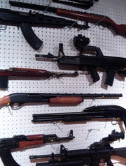 An assortment of modern handheld firearms using fixed ammunition, including military assault rifles, a sporting shotgun (fourth from bottom), and a tactical shotgun (third from bottom).