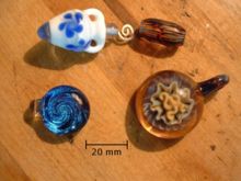 Hand-blown glass beads and pendants illustrate some of the myriad colors and shapes of glass art. The Canadian Nickel is for scale.